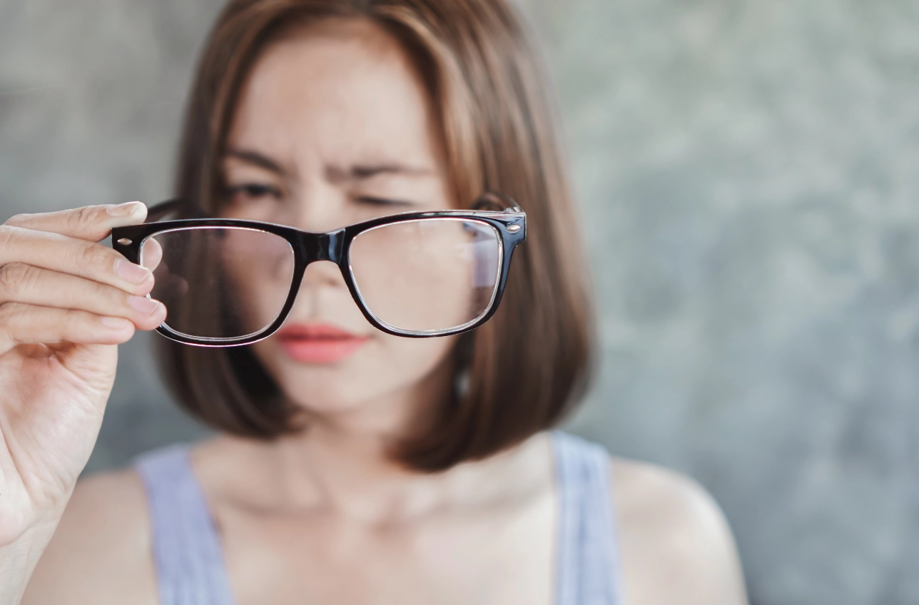 Femme tenant une paire de lunette devant ses yeux 